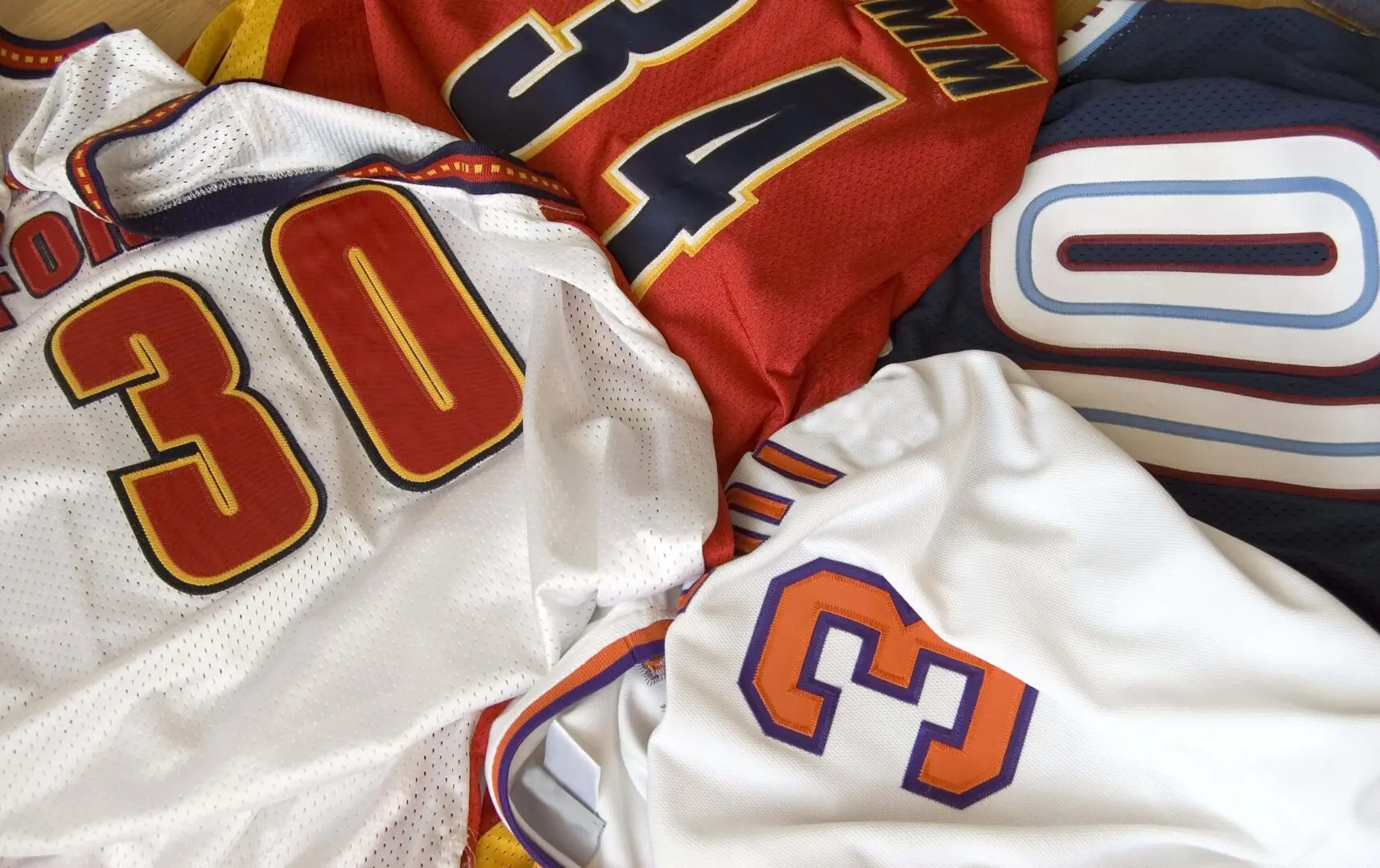 Close-up of colorful sports jerseys with numbers on them.