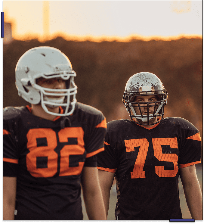 Two football players in black and orange uniforms standing side by side.